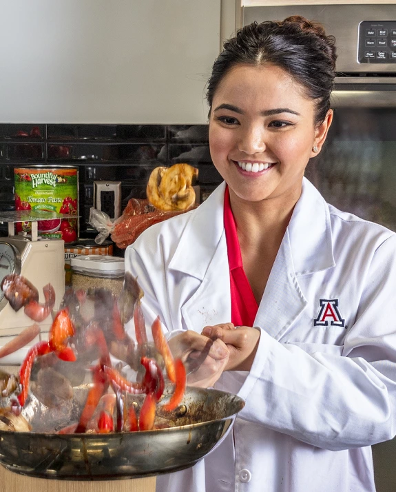 A nutritional sciences student cooks peppers in the food lab.
