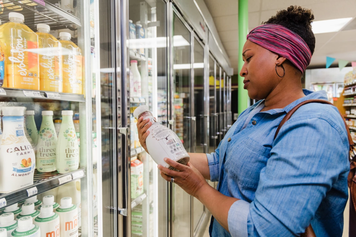 A woman shops for non-dairy milk at a grocery store