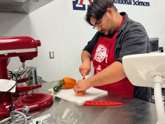 Student cutting bell peppers in a University of Arizona kitchen space.