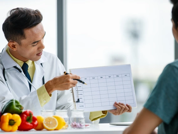 A nutritionist pointing to a dietary schedule for their client.