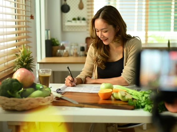 A person writing down nutritional facts in their kitchen.